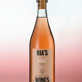 A bottle of Ria's Wines rosé, featuring a clear glass bottle filled with pinkish-rose liquid, a beige label, and a cork closure, set against a soft pink and white gradient background.